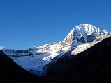 42 Mount Kailash East And North Faces And Jagged Shama Ri East Ridge From Just Beyond Dirapuk On Mount Kailash Outer Kora The trail from Dirapuk crosses a bridge and follows a broad shelf above the Dolma Chu. After only 30 minutes a perfect view of the start of the Mount Kailash East Face comes into to the east of the North Face. The north side of the sharp jagged ridge called Shama Ri, extends to the east of Mount Kailash. This ridge represents the 18 Hells: 8 Cold, 8 Hot, and 2 Trial Hells. Its treacherous appearance serves as a sober reminder to pilgrims that hell exists and perhaps looks like this. A short truncated glacier with a small but distinct terminal, lateral, and medial moraines descends from the rocky eastern arm of the east and north faces of Kailash, down through the Polung Valley between the Avalokiteshvara (Tib. Chenrezig)  and Manjushri (Tib. Jampelyang) peaks.